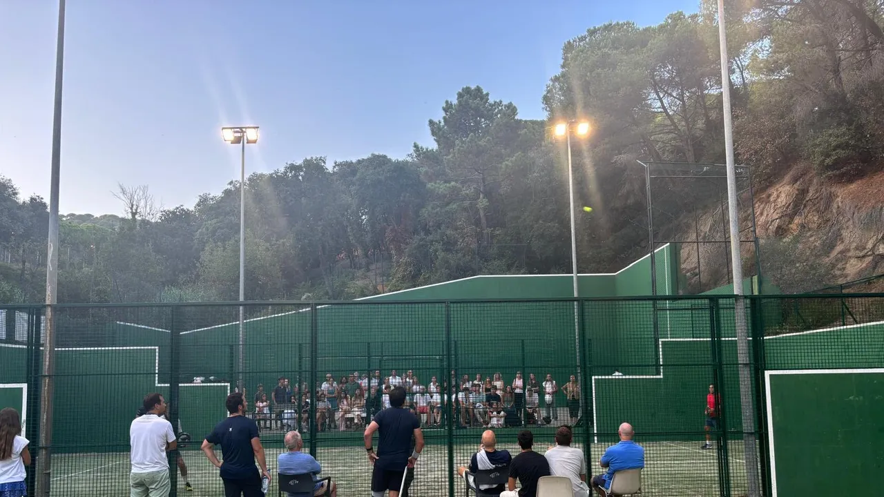 Pistas de pádel del C.N. El Balís al anochecer durante la final del torneo 2025, con público siguiendo el partido.