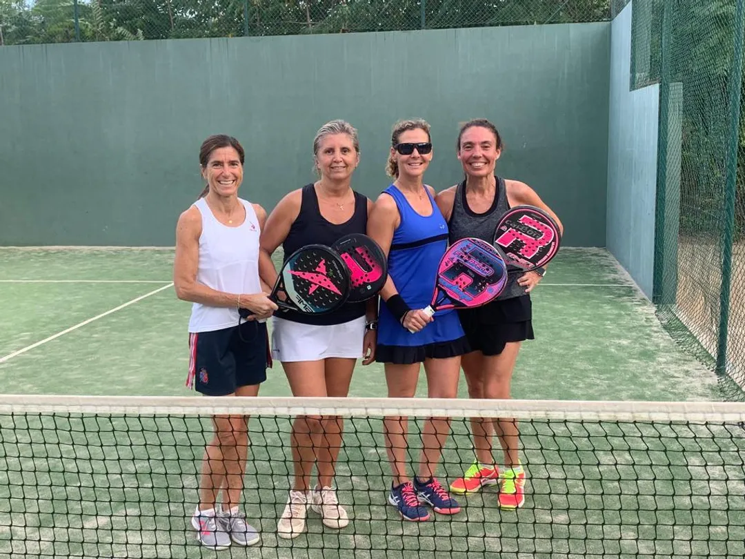 Cuatro jugadoras posando con sus palas junto a la red en la pista del torneo Padelgazar 2024.
